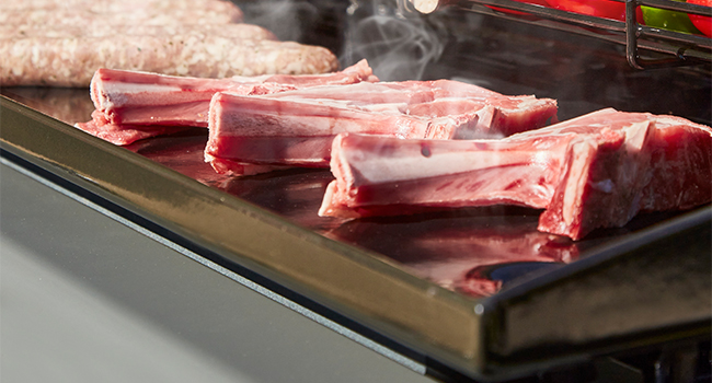 Séquence rapprochée montrant des portions de viande crue sur une surface sombre ou une plate-forme de cuisson.